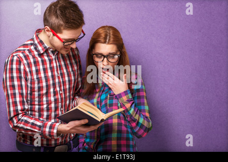 Jeune couple en vêtements et lunettes hippie chic en lisant un livre. studio shot Banque D'Images