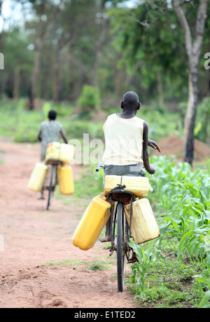 Recueillir l'eau des enfants sur leurs vélos dans la région de Nakasongola en Ouganda Banque D'Images