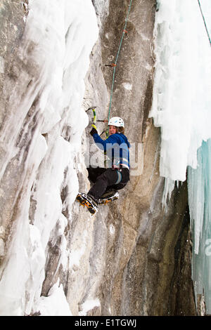 Jeune femme grimpe dans un mélange de glace et de roche tandis que l'escalade sur glace dans le parc national de Banff, près de Banff, Alberta, Canada. Banque D'Images