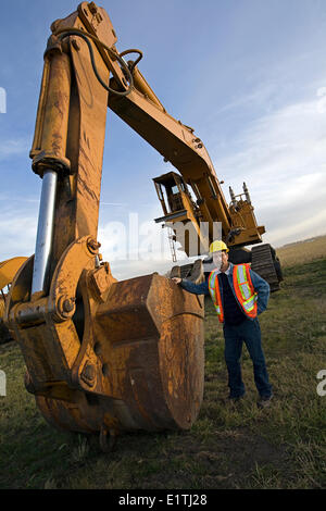 Opérateur d'équipement lourd debout à côté de l'excavation de la machine. Banque D'Images