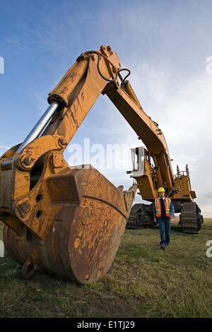 Opérateur d'équipement lourd marche à côté de l'excavation de la machine. Banque D'Images