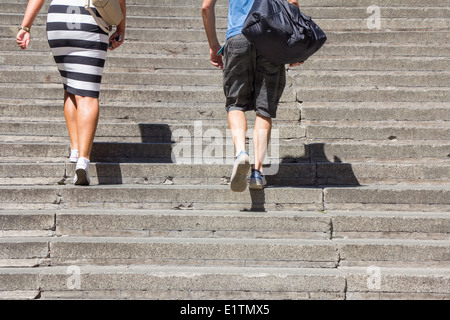 Une femme et l'homme grimpant sur des escaliers en béton Banque D'Images