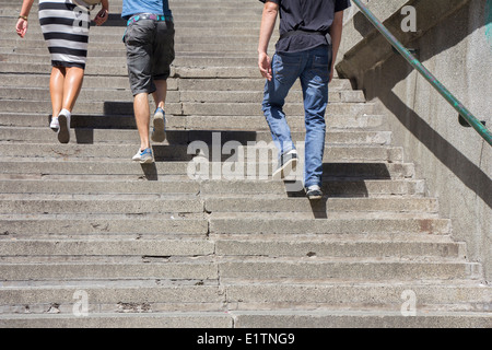 Une femme et deux homme grimper sur l'escalier en béton Banque D'Images