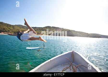 Un jeune homme saute du bateau-taxi pour aller surfer. San Juan del Sur, Nicaragua Banque D'Images