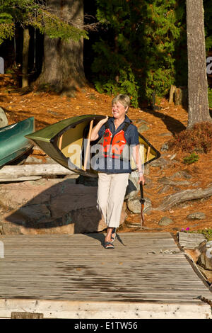 Femme mature porte canot au lac Source, parc Algonquin, Ontario, Canada. Banque D'Images