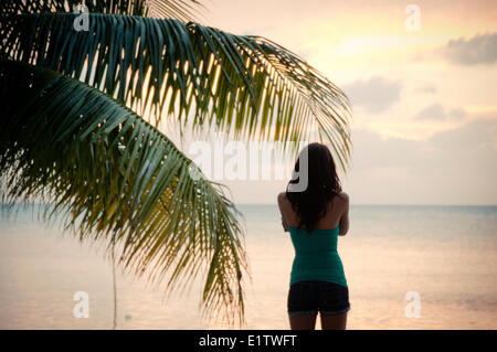 Une jeune femme pour le coucher du soleil sur Caye Caulker, Belize. Banque D'Images