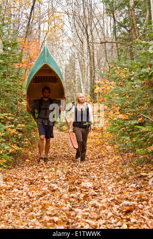 Jeune couple portage canoe dans le nord-ouest de l'extrémité du parc Algonquin, Ontario, Canada. Banque D'Images