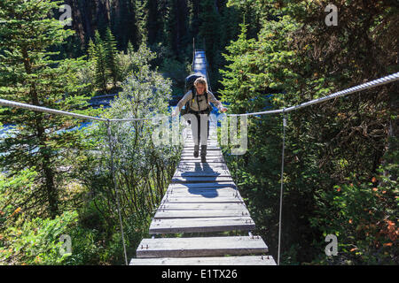 Une femelle backpacker traverse le ruisseau ocre après une descente de la Paroi rocheuse en route vers les pots de peinture de la piste Parc national Kootenay Banque D'Images