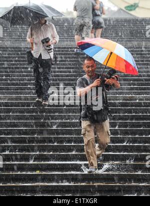 Beijing, Chine. 10 Juin, 2014. Marcher dans les photographes étapes de la pluie à l'extérieur du National Centre for the Performing Arts (NCPA) à Beijing, capitale de Chine, le 10 juin 2014. Une pluie torrentielle a frappé la capitale mardi après-midi. Credit : Luo Xiaoguang/Xinhua/Alamy Live News Banque D'Images