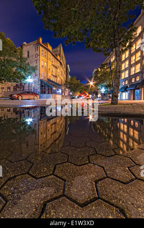 Édifices du patrimoine se reflétant dans une flaque d'eau dans le quartier de la Bourse du centre-ville de Winnipeg, au crépuscule. Manitoba, Canada. Banque D'Images