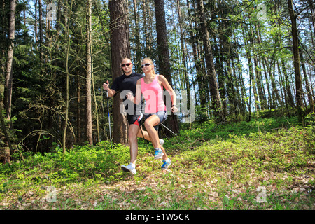 Un couple marche nordique à travers forêts Formation Banque D'Images