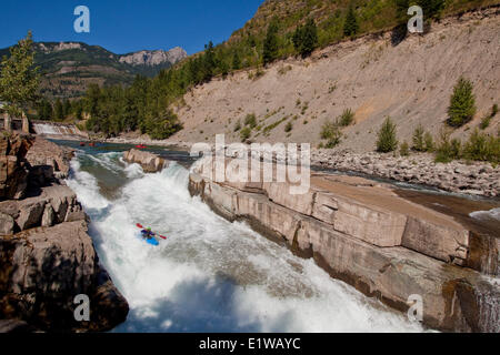 Un homme court le kayakiste difficile section du haut de la rivière Elk, Fernie, BC Banque D'Images