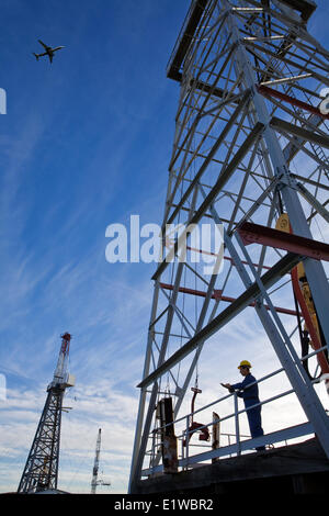 Oil drilling rig travailleur avec avion volant au-dessus, l'Alberta, Canada Banque D'Images