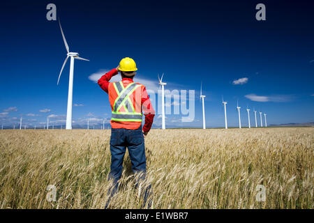 Technicien en énergie éolienne debout à côté d'éolienne, près de Pincher Creek, en Alberta. Banque D'Images
