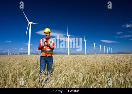 Technicien en énergie éolienne debout à côté d'éolienne, près de Pincher Creek, en Alberta, Canada. Banque D'Images