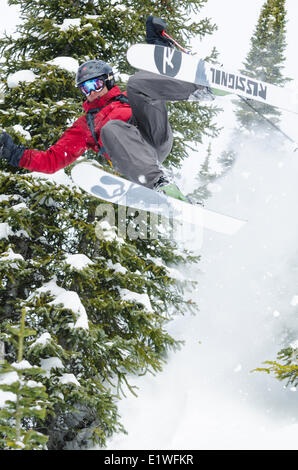 Un skieur masculin prend un saut de contrôle tandis que le ski dans la région de Kootenay, Colombie-Britannique Banque D'Images