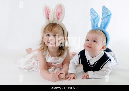 Jeune garçon et fille porter des oreilles de lapin, tout en regardant vers le haut et souriant Banque D'Images