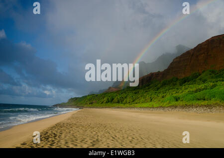 Un arc-en-ciel arcs vers le bas de la montagne à la plage sur le Kalalau trail, Na'Pali Coast, Kaua'i Banque D'Images