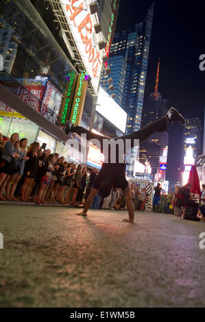 Artiste de rue se tient sur ses mains au cours d'une performance athlétique sur Times Square à New York Banque D'Images