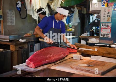 Vendeur de poisson sculpture soigneusement à l'aide de morceaux de thon un long couteau appelé-oroshi hocho au marché Tsukiji. Une grande attration Banque D'Images