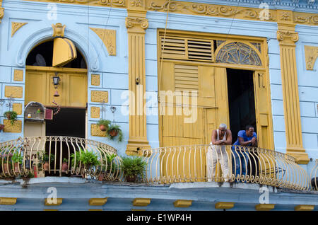 Façade bâtiment coloré avec des hommes sur le balcon, à La Havane, Cuba Banque D'Images