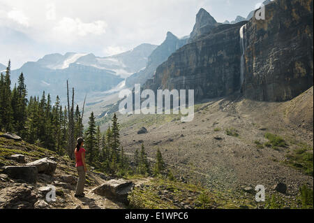 Un randonneur fait une pause sur le sentier pour admirer la cascade le long du sentier du glacier Stanley, dans le parc national Kootenay. Communiqué de modèle Banque D'Images