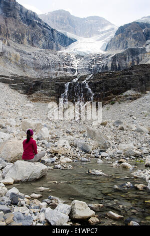 Un randonneur est assis sur un rocher à côté d'une eau de piscine alimentée par le glacier Stanley. Forêt à proximité de fumée flottant sur les montagnes. Model Banque D'Images