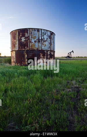 Conteneur de stockage d'huile abandonnés avec groupe de pumpjack en arrière-plan, l'Alberta, Canada. Banque D'Images