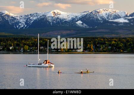 Trois kayakistes paddle vers leur trimaran près de Comox (C.-B.). Les montagnes en arrière-plan sont sur l'île de Vancouver, BC. Banque D'Images