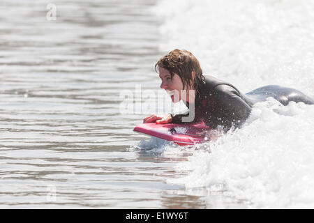 Une femme mature expereinces le plaisir du body surfing sur Chesterman Beach près de Tofino. Rives du Pacifique l'île de Vancouver, Colombie-Britannique Banque D'Images