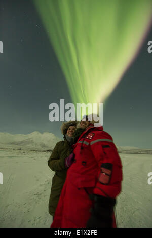 Heureux couple debout sous les aurores boréales, Yukon. Banque D'Images