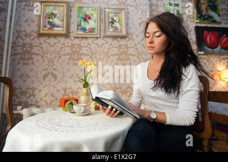 Beautiful young woman reading book in cafe Banque D'Images