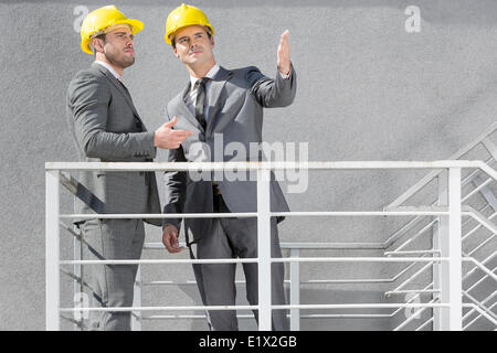 Deux jeunes hommes d'un casque de discuter sur l'escalier Banque D'Images