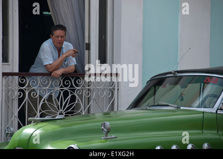 Homme cubain fumant un cigare près d'une voiture américaine d'époque à Cienfuegos, Cuba Banque D'Images