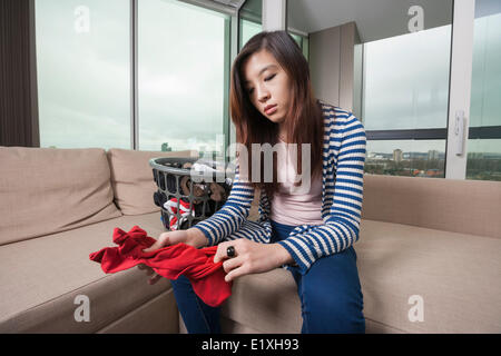 Young woman doing laundry travailler dans la salle de séjour à la maison Banque D'Images