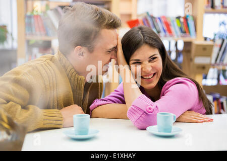 Jeune couple ludique avec les tasses de café sur le bureau dans la bibliothèque Banque D'Images