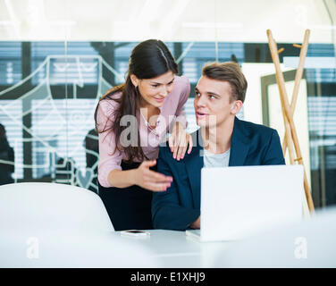 Young businessman with female colleague discussing over laptop in office Banque D'Images