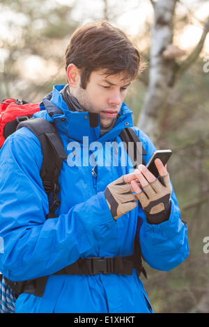 Young male hiker using smart phone in forest Banque D'Images