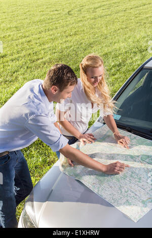 High angle view of couple reading map sur un capot de voiture en road trip Banque D'Images