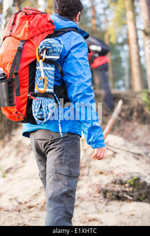 Vue arrière du male hiker with backpack standing in forest Banque D'Images