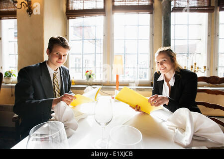 Portrait of smiling business couple avec menus au restaurant table Banque D'Images