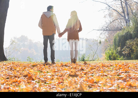 Vue arrière du couple holding hands in park au cours de l'automne Banque D'Images