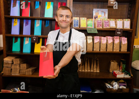 Portrait d'homme vendeur montrant produit en magasin café Banque D'Images