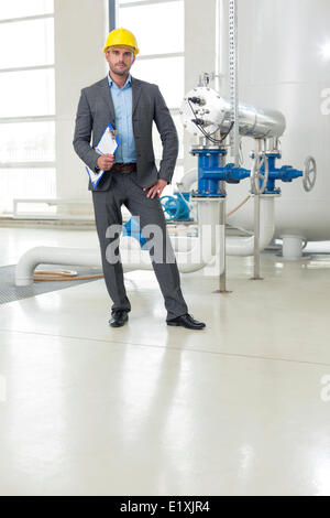 Portrait de jeune homme confiant avec gestionnaire de presse-papiers dans l'industrie Banque D'Images