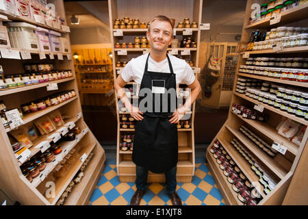 Full Length portrait of mid adult salesman standing hands on hips in grocery store Banque D'Images