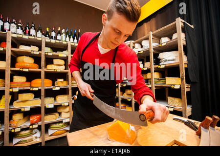 Vendeur mâle la découpe du fromage en magasin Banque D'Images