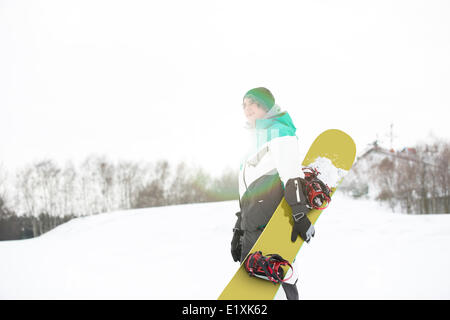 Jeune homme avec snowboard walking in snow Banque D'Images