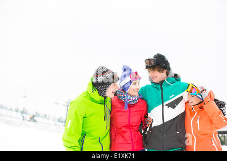 Cheerful young friends standing autour du bras dans la neige Banque D'Images