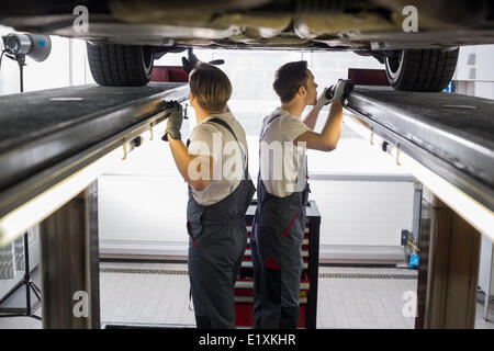 Vue latérale d'ingénieurs de maintenance l'examen de voiture dans l'atelier de réparation Banque D'Images