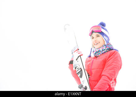 Smiling young woman carrying skis dans la neige Banque D'Images